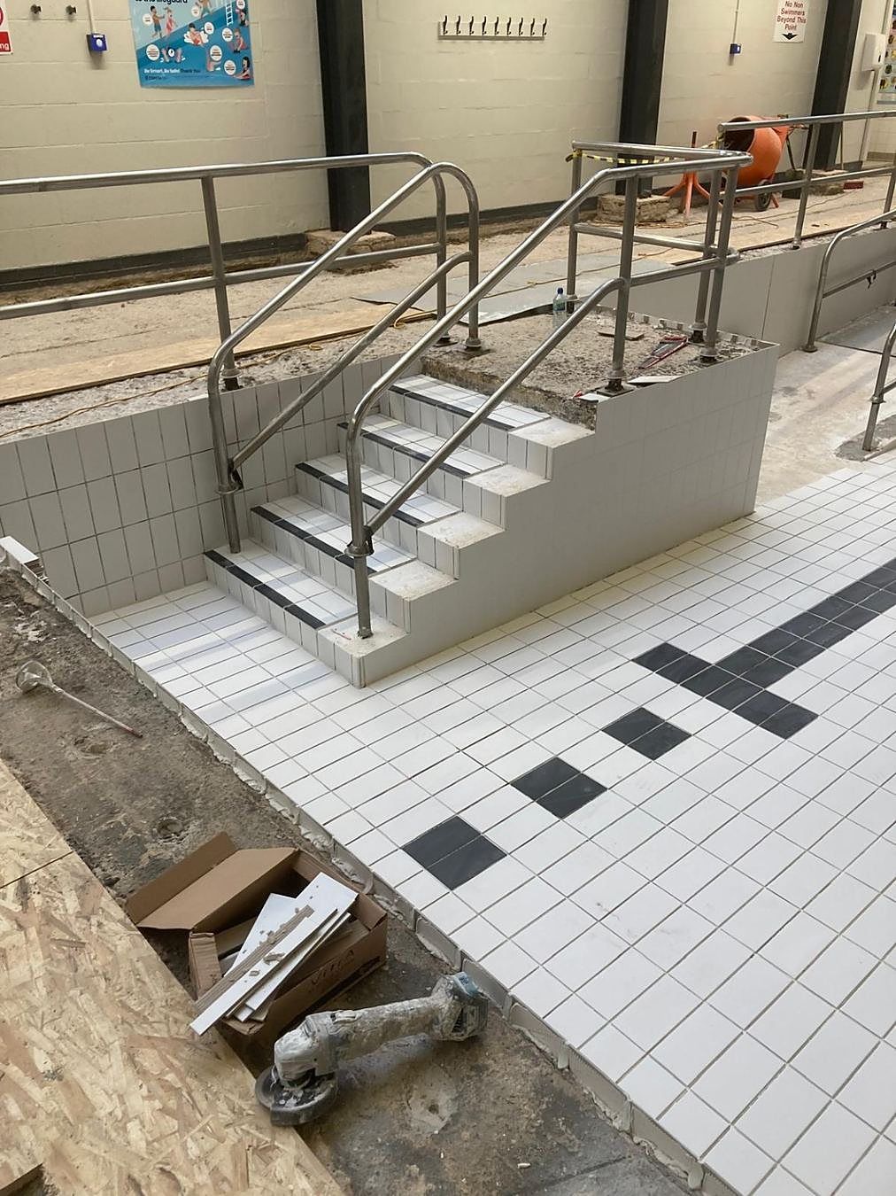 New pool-wall and access-step tiling in place, with the handrails fitted.