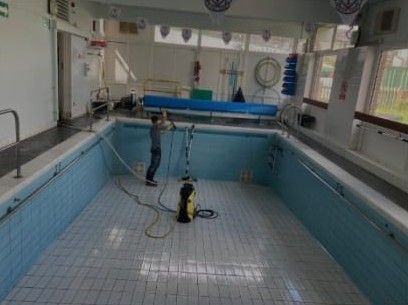 Drained pool being cleaned with a pressure washer