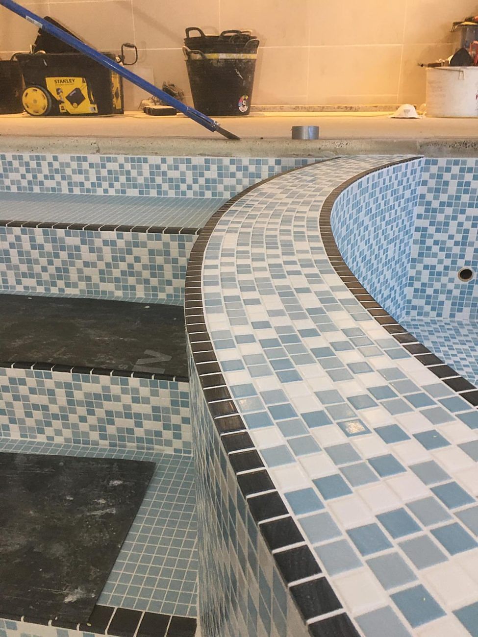 The curved bench top finished with black edge tiles, beside the stepped entry.