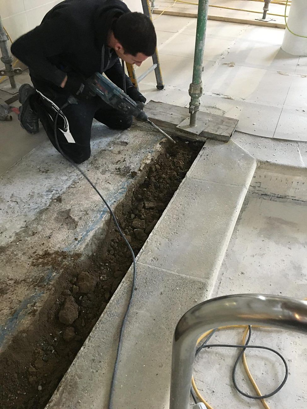 The old drainage channel being broken out along the pool edge.