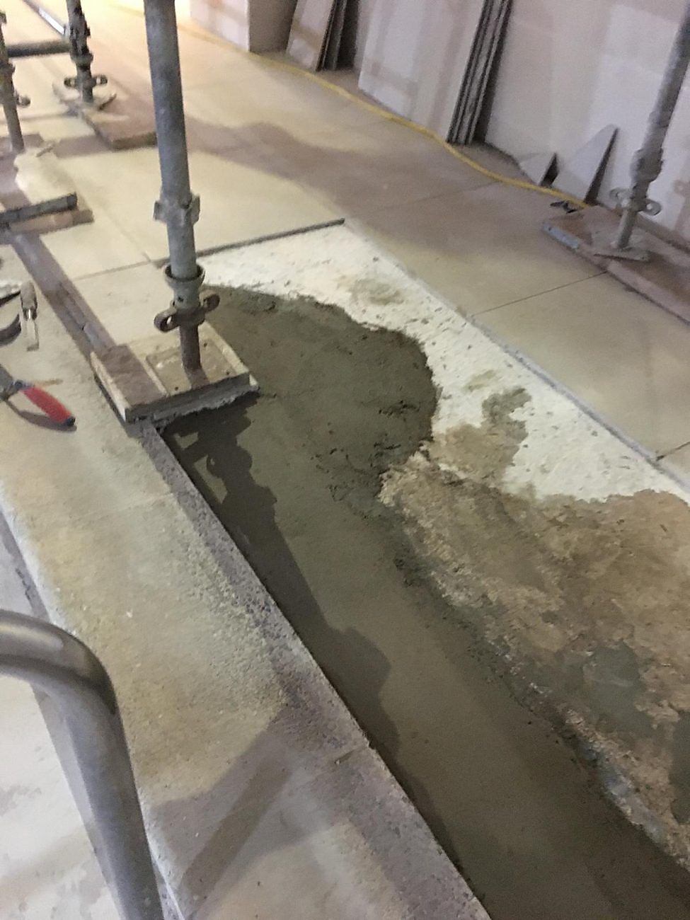 Fresh screed laid along the broken-out drainage channel.