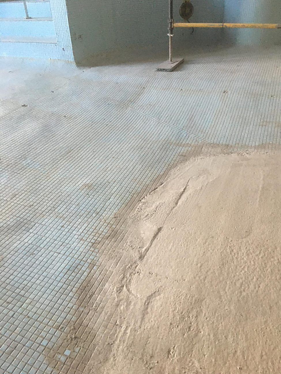 Before: the original blue mosaic floor, with the first section lifted back to bare adhesive.