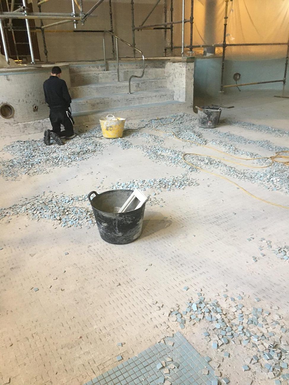 The rip-out under way across the basin, with broken-out mosaic piled for removal.
