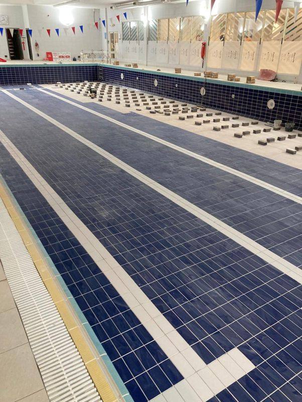 Navy floor tiles going down, with new tiles set out across the floor.